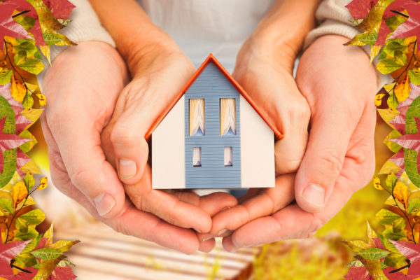 man and child's hands holding model of house symbolizing fall home maintenance
